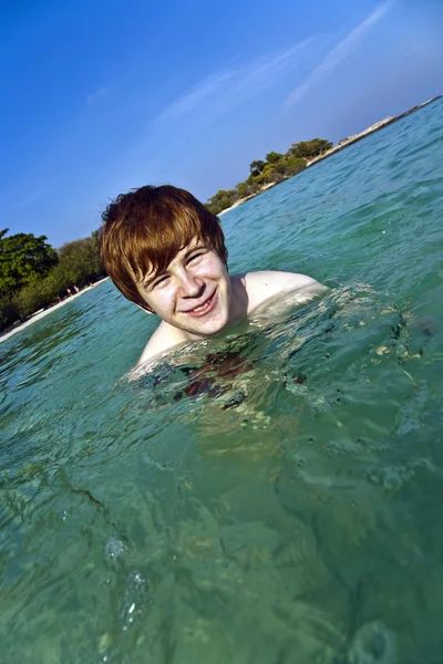 Vörös hajú fiú élvezi a kristálytiszta víz a tengerben — Stock Fotó