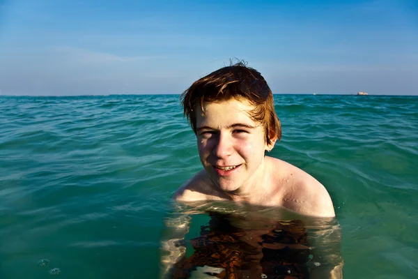 Vörös hajú fiú élvezi a tiszta meleg víz a gyön — Stock Fotó