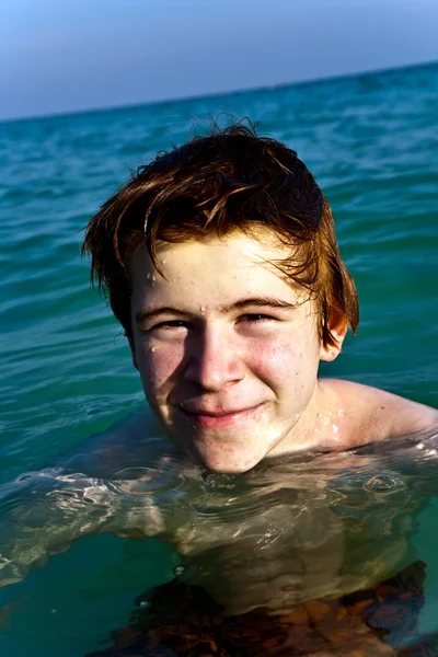 Jongen met rood haar is genieten van het duidelijk warm water op de beauti — Stockfoto