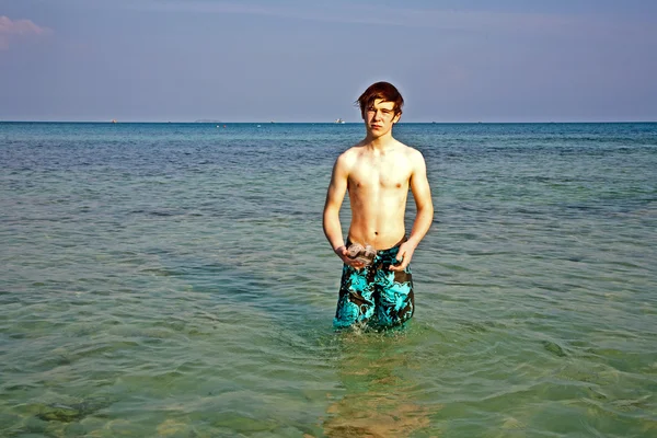 Молодой мальчик стоит в красивом чистом море — стоковое фото