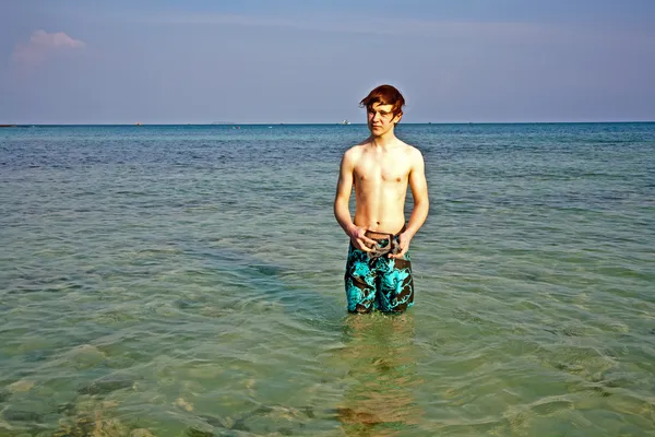 Genç çocuk içinde güzel bir açık deniz kenarında duruyor — Stok fotoğraf