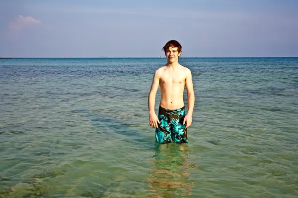 Ung pojke står i det vackra kristallklara havet — Stockfoto
