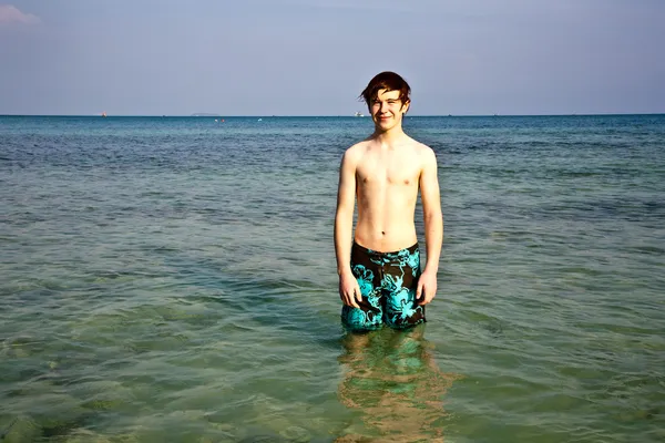 Jovem rapaz está de pé no belo mar claro — Fotografia de Stock