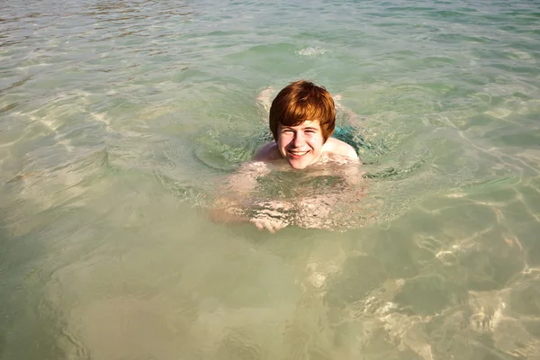 男孩在美丽的明确海洋中游泳 — 图库照片