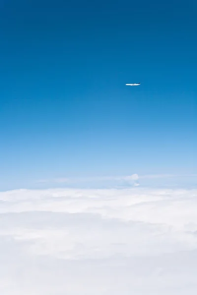Самолет, летящий над облаками — стоковое фото