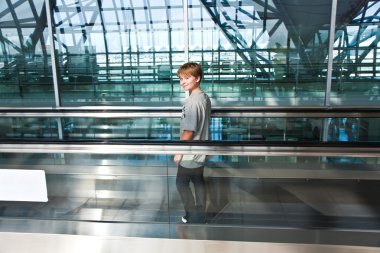 Boy in the departure hall in the new Airport on a moving stairc clipart