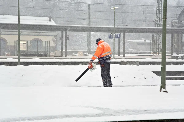 श्रमिक बर्फ से एक ट्रेन स्टेशन के प्लेटफॉर्म को साफ कर रहा है — स्टॉक फ़ोटो, इमेज