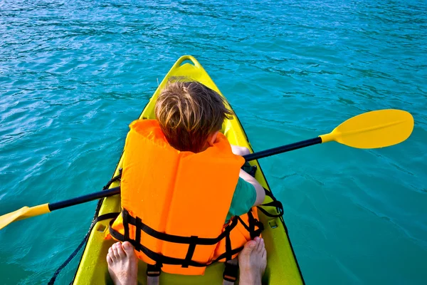 Chico rema en una canoa en el océano con seguridad al oeste — Foto de Stock