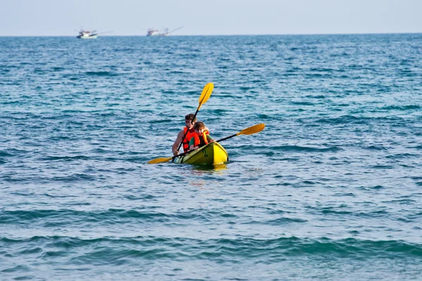 Far och son är padelling med en kanot på öppet hav — Stockfoto