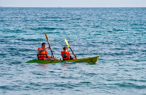 Padre e hijo están acolchados con una canoa en mar abierto —  Fotos de Stock