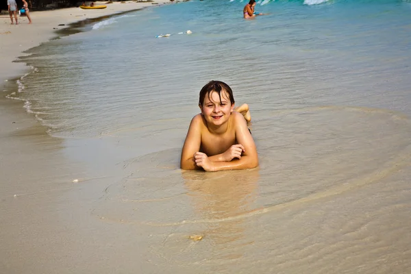 Kleiner Junge liegt am Strand und genießt die Wärme der Sonne — Stockfoto