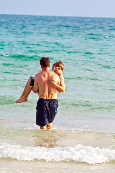 Pai está segurando seu filho nos braços na bela bea arenosa — Fotografia de Stock