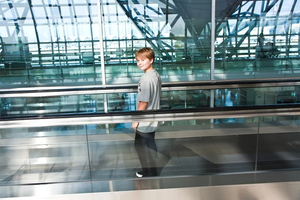 Мальчик в зале вылета в новом аэропорту на движущейся лестнице — стоковое фото