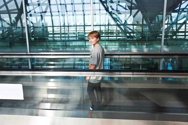 Junge in der Abflughalle des neuen Flughafens auf einer Rolltreppe — Stockfoto