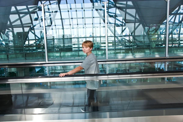 Niño en la sala de salida en el nuevo aeropuerto en una escalera en movimiento —  Fotos de Stock