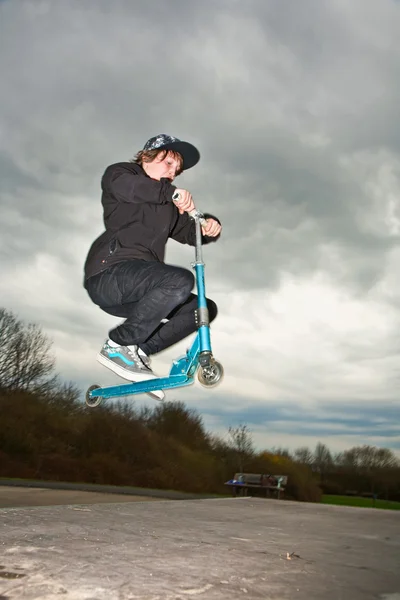 Menino montando uma scooter e indo para o ar em um parque de scooter — Fotografia de Stock