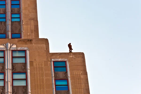Πρόσοψη του ουρανοξύστη με το άγαλμα του ανθρώπου — Φωτογραφία Αρχείου