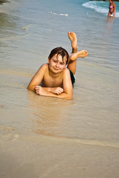 Fiatal fiú fekszik a strandon, és a melegét élvezi az — Stock Fotó