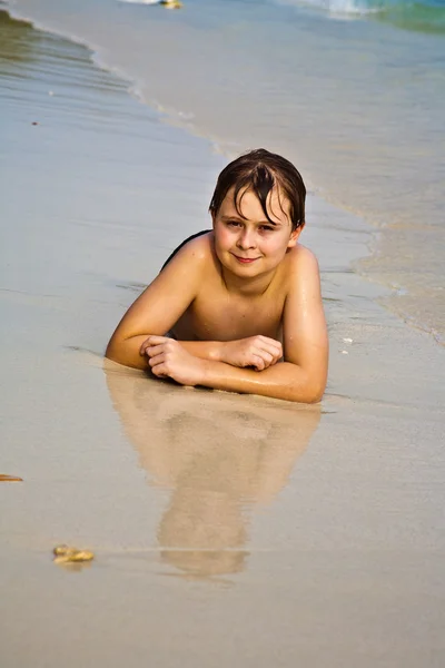 年轻的男孩是躺在沙滩上，享受着的暖意 — 图库照片