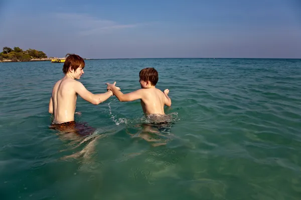 Fratelli stanno godendo l'acqua calda e limpida al bellissimo mare Foto Stock Royalty Free
