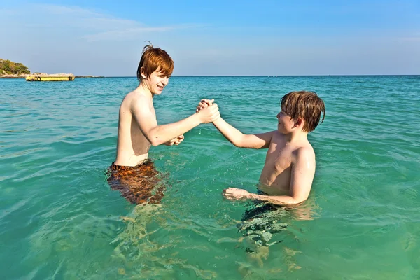 Fratelli stanno godendo l'acqua calda e limpida al bellissimo mare Immagine Stock