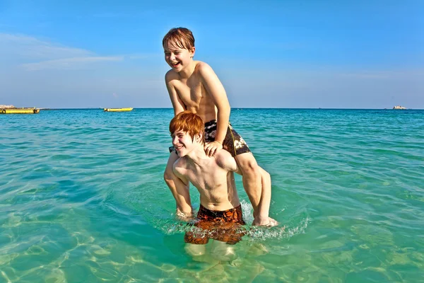 Fratelli stanno godendo l'acqua calda e limpida al bellissimo mare Fotografia Stock