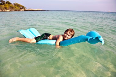 Boy enjoys the cristal clear water in the ocean clipart