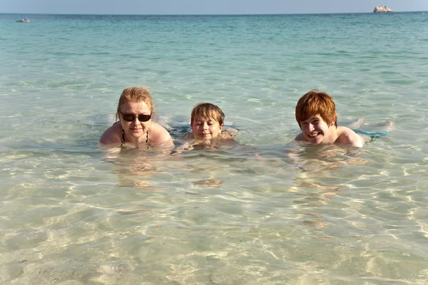 Семья с рыжими волосами лежит в море на прекрасном пляже и наслаждается — стоковое фото