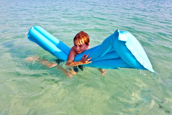 Мальчику нравится воздушный матрас в море — стоковое фото