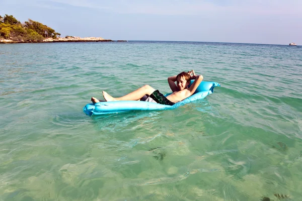 Chico disfruta del colchón de aire en el mar caliente claro —  Fotos de Stock