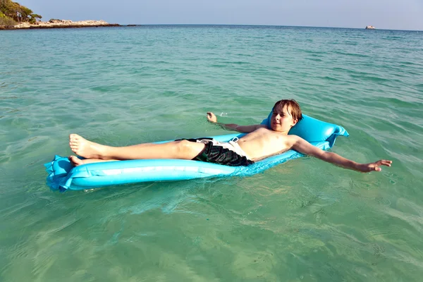 Chico disfruta del colchón de aire en el mar caliente claro —  Fotos de Stock