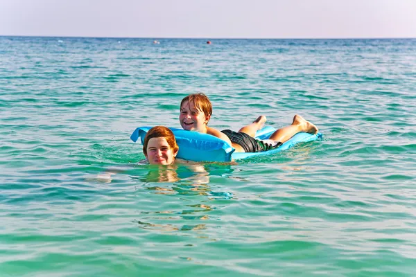 Brothers enjoy playing together in teh crystal clear ocean — Stock Photo, Image