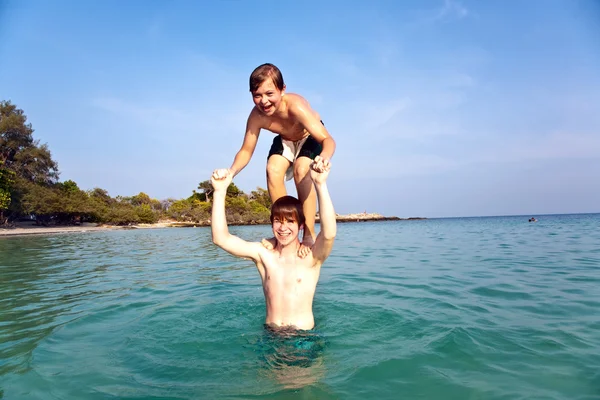 Hermanos jugando juntos pickapack en el hermoso océano —  Fotos de Stock