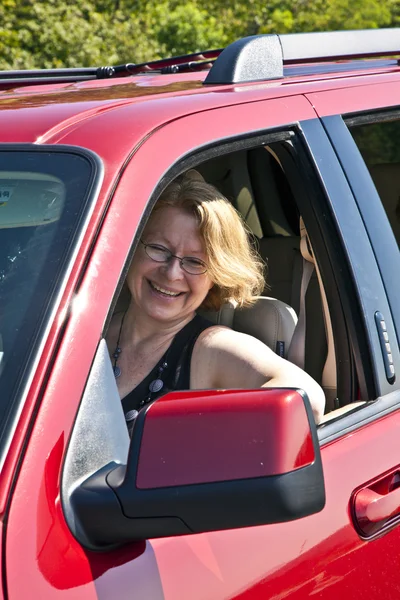 Leende kvinna kör en röd bil — Stockfoto