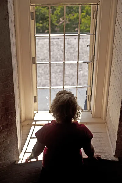 Mulher olhando de uma janela — Fotografia de Stock