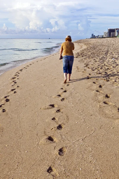 Kvinnan vandrar längs stranden — Stockfoto