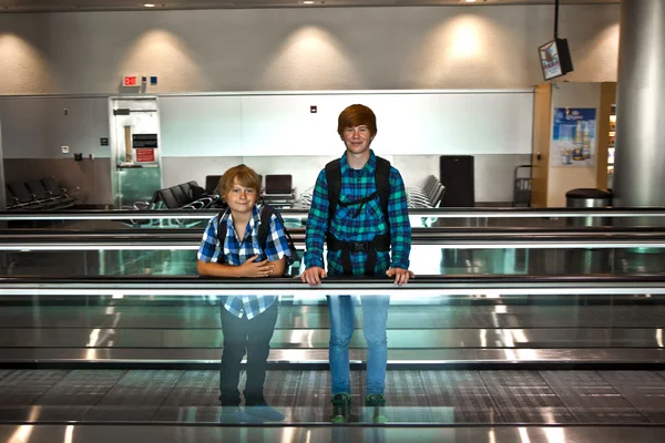 Young boys on a moving staircase inside the airport — Stock Photo, Image