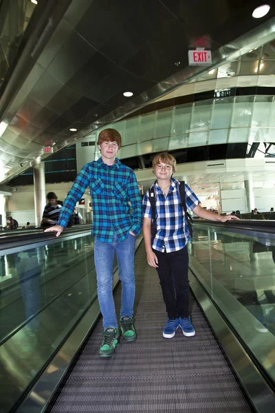 Young boys on a moving staircase inside the airport — Stock Photo, Image