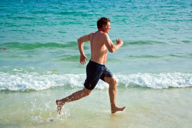 Man is running along the beautiful beach clipart