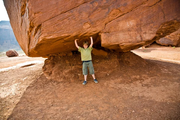 Monument Valley, el niño se divierte simulando llevar un gran roc —  Fotos de Stock