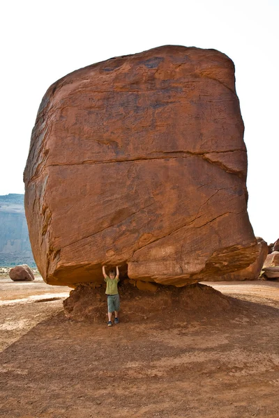 Monument Valley, el niño se divierte simulando llevar un gran roc —  Fotos de Stock