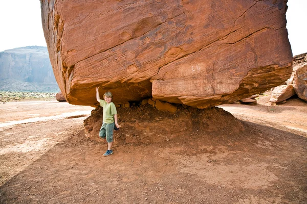 Monument Valley, il bambino si diverte simulando di portare una grande roccia — Foto Stock