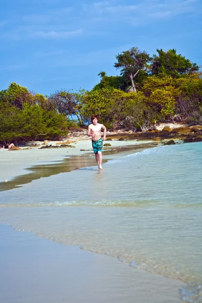 Kleiner Junge mit roten Haaren im Badeanzug läuft am schönen Strand entlang — Stockfoto