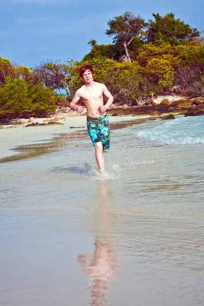 수영복에 붉은 머리를 가진 어린 소년 아름 다운 해변을 따라 실행 — 스톡 사진
