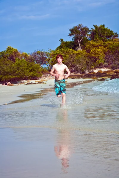 Jongen met rood haar in zwembroek draait langs het prachtige strand — Stockfoto