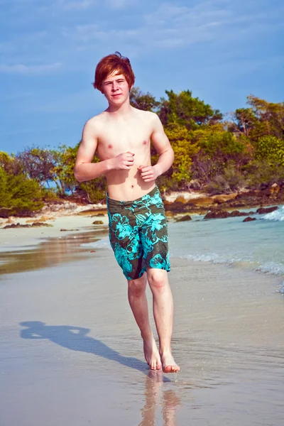 穿泳衣的红头发的小男孩正在运行沿美丽的海滩 — 图库照片