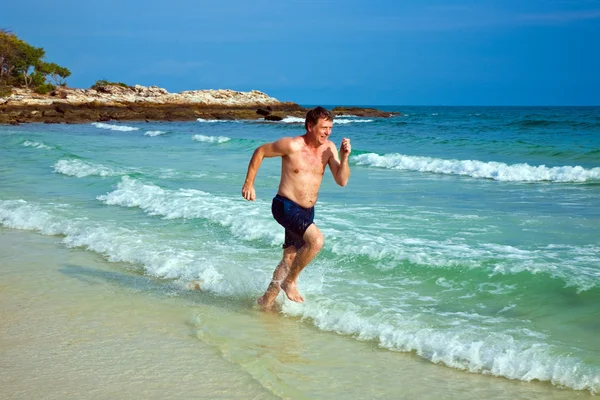 Adam güzel plaj boyunca koşuyor — Stok fotoğraf