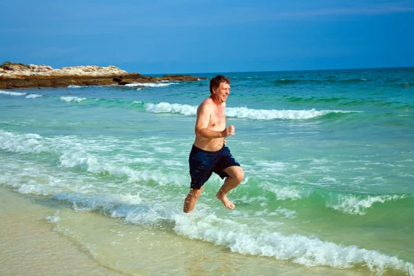 Homem está correndo ao longo da bela praia — Fotografia de Stock