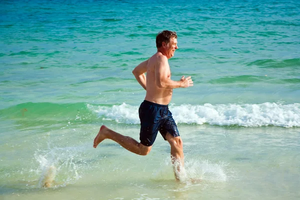 Az ember a gyönyörű strand mentén fut. — Stock Fotó