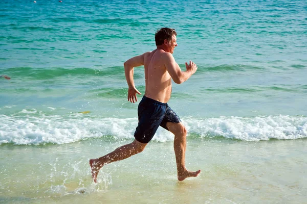 Чоловік біжить уздовж прекрасного пляжу — стокове фото
